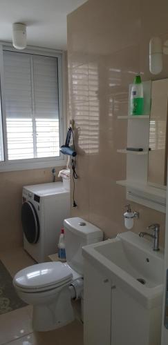 a bathroom with a white toilet and a sink at 2 BDR Nitza appartment with balkony in Netanya