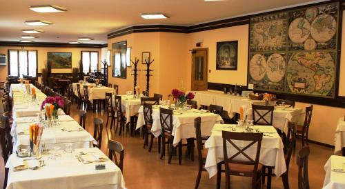 a restaurant with tables and chairs with white tablecloths at Hotel Des Alpes in Castione della Presolana