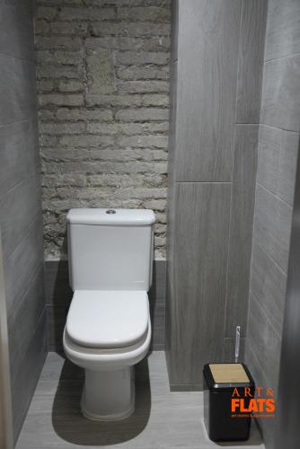 a white toilet in a bathroom with a brick wall at Art&Flats Hostel in Valencia