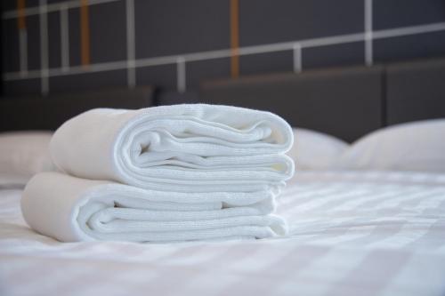 a stack of white towels sitting on a bed at Hallton Hotel Bangkok in Bangkok