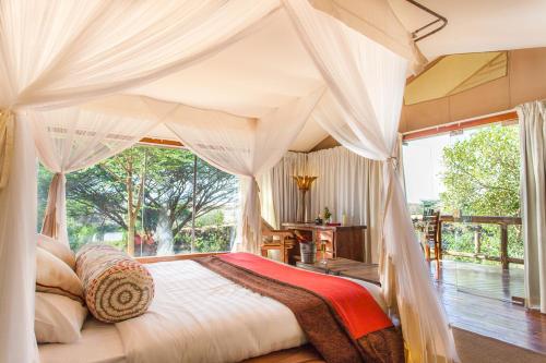 a bedroom with a canopy bed with a large window at Mara Leisure Camp in Talek