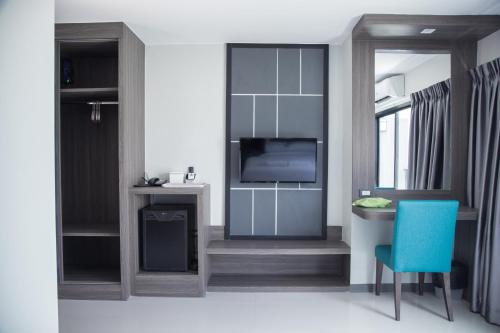 a living room with a tv and a blue chair at Hallton Hotel Bangkok in Bangkok