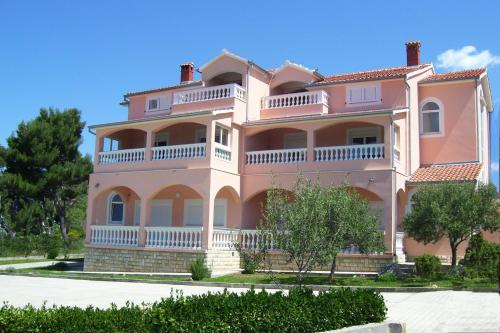 a large pink house with a balcony at Rooms & Apartments Linda & Mario in Zadar