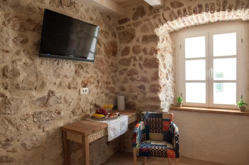 a living room with a tv on a stone wall at Sobe Bile in Pag