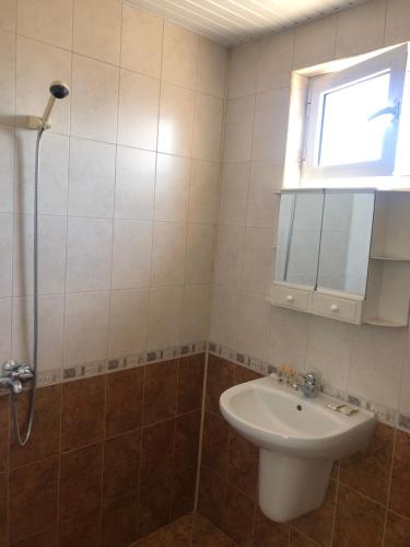 a bathroom with a sink and a shower with a window at Guest House Rai in Kiten