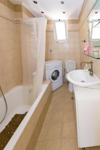 a bathroom with a tub sink and a washing machine at Analipsi House Afrodite in Kástro Tornéze