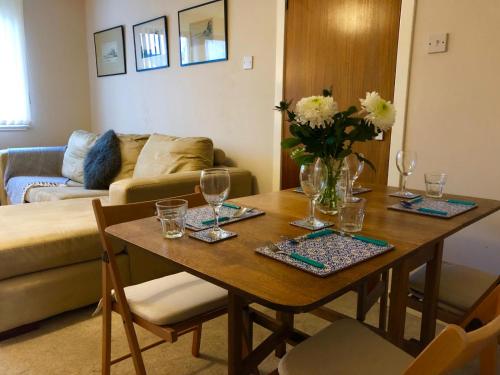 a living room with a table with glasses and flowers on it at But & Ben in Balloch in Balloch