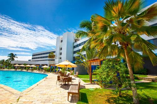 un complexe avec une piscine, des palmiers et un bâtiment dans l'établissement Del Mar Hotel, à Aracaju