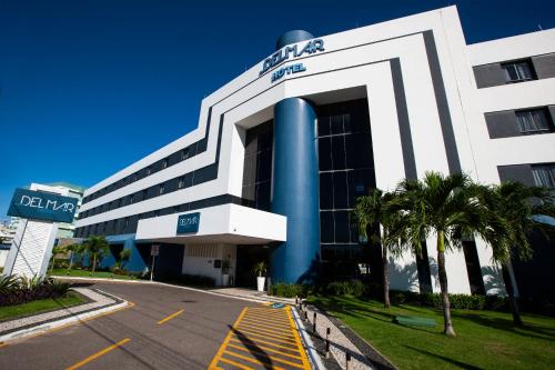 a large white building with palm trees in front of it at Del Mar Hotel in Aracaju