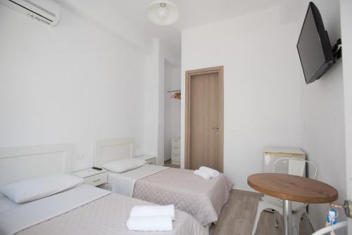 a room with two beds and a table and a television at Lovely Studios In Mykonos Old Town in Mýkonos City