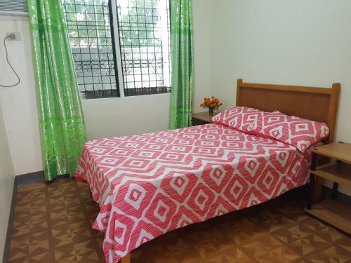 a bedroom with a red and white bed and a window at OMG Guesthouse Room for 2 in Licup