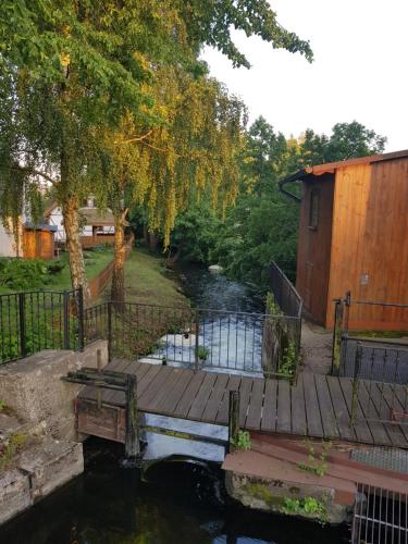 a wooden bridge over a river next to a house at Chata Pod Strzechą in Lipusz