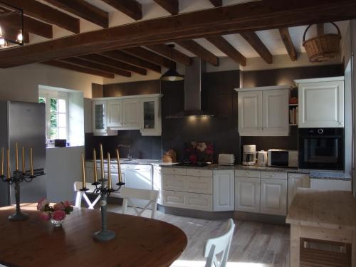 a kitchen with white cabinets and a wooden table at Au calme dans la campagne du Haut Anjou in Pouancé