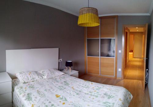 um quarto com uma cama e uma luz pendente em Apartamento con piscina en Foz em Foz