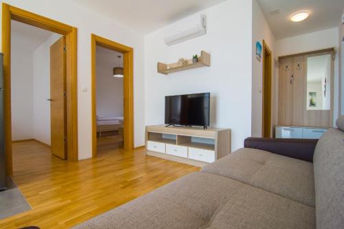 ein Wohnzimmer mit einem Sofa und einem Flachbild-TV in der Unterkunft Villa Nikola - big terrace apartments in Bol