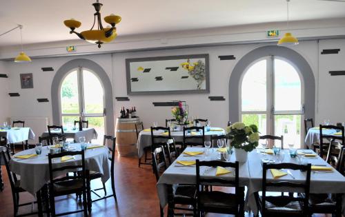 Auberge Béarn Bigorre في Lamarque-Pontacq: غرفة طعام مع طاولات وكراسي ونوافذ