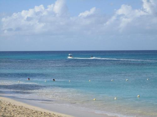 a group of people in the ocean with a boat at Tropical Sunset Beach Apartment Hotel in Saint James