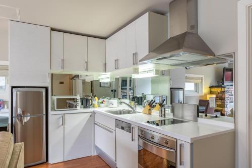 a kitchen with white cabinets and stainless steel appliances at Fresh Powder Accommodation in Furano