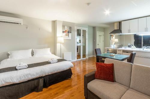 富良野的住宿－新鮮的粉末公寓式酒店，一间卧室配有一张床和一张沙发,还设有一间厨房