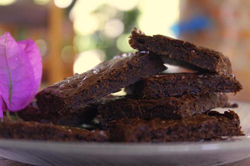 a pile of brownies on a plate with a flower at Pousada Morada do Sol in Canoa Quebrada