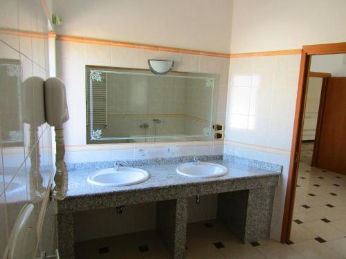 uma casa de banho com 2 lavatórios e um espelho grande em Grand Hostel Calabria em Pietrapaola