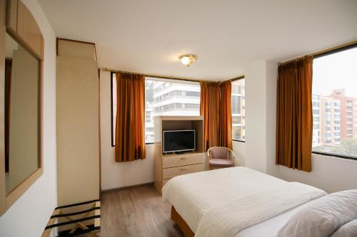 Habitación de hotel con cama y TV en Stanford Suites Hotel, en Quito