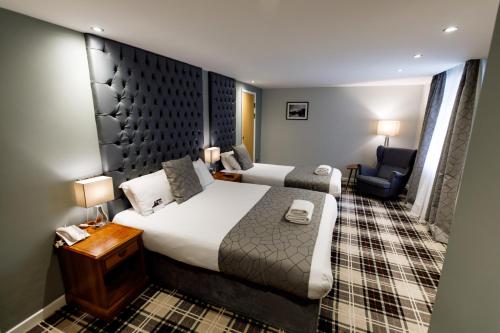 a hotel room with a bed and a chair at The Heritage Park Hotel in Pontypridd