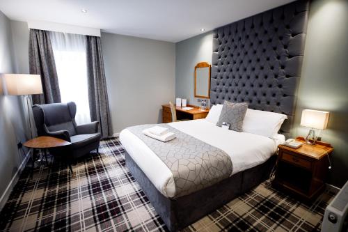 a hotel room with a bed and a chair at Heritage Park Pontypridd, Trademark Collection by Wyndham in Pontypridd