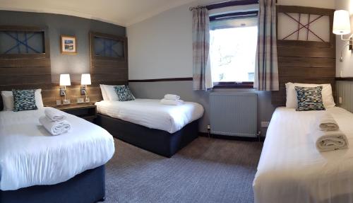 a hotel room with two beds and a window at Clachaig Inn in Ballachulish