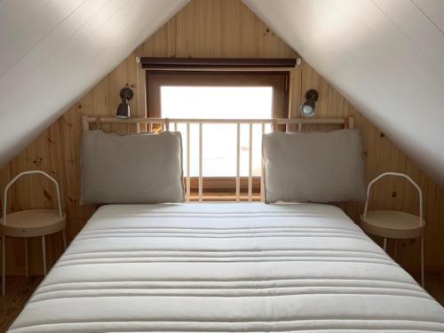 Cama en habitación con 2 sillas y ventana en Small Vinter Summer House en Käsmu