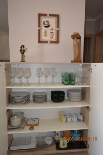 a shelf with plates and glasses in a kitchen at Dreamlodge - Luxe Dalmatian Villa, private pool, parking, mooring, breathtaking sea & mountain view, at 150 m from idyllic private beach in Rogač