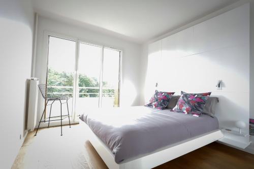 a white bedroom with a bed and a large window at The Sparkling Castle in Reims