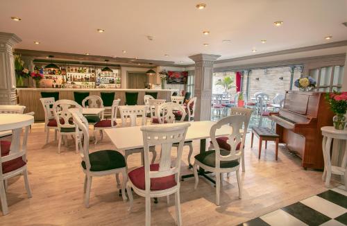um restaurante com mesas e cadeiras brancas e um bar em Hotel Vintage em Bogotá