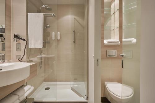 a bathroom with a shower and a toilet and a sink at H2 Hotel Berlin-Alexanderplatz in Berlin