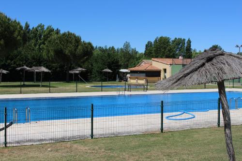 una gran piscina con sombrilla de paja en Hostal Las Paneras en Avila