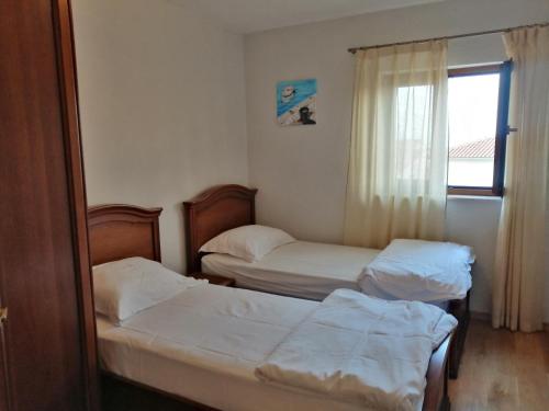 two beds in a small room with a window at Casa Emma in Krk