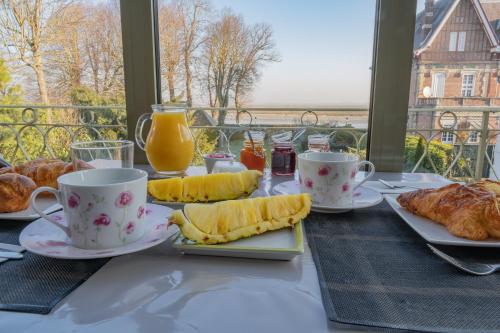 une table recouverte de tasses et d'assiettes de nourriture pour le petit-déjeuner dans l'établissement Chambres avec Vue, à Saint-Valery-sur-Somme