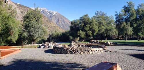 a park with a pile of logs and trees and mountains at SEL Lodge - Aventura y Descanso in San José de Maipo