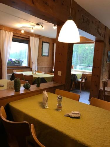 a dining room with a yellow table and chairs at Hotel Val d`Arca in Stampa