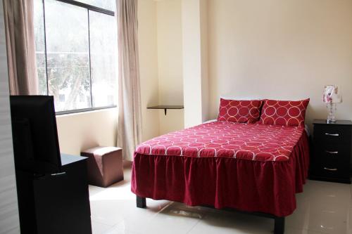 1 dormitorio con cama roja y ventana en Hostal du Parc, en Trujillo