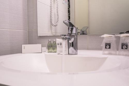 La salle de bains est pourvue d'un lavabo, d'un robinet et d'un miroir. dans l'établissement Hotel Actuel Chambéry Centre Gare, à Chambéry