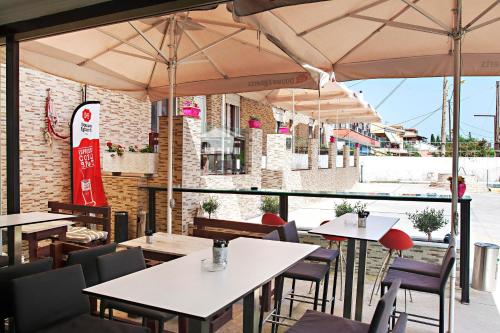 un restaurante con mesas, sillas y sombrillas en Spiridoula's Apartments Corfu, en Perama
