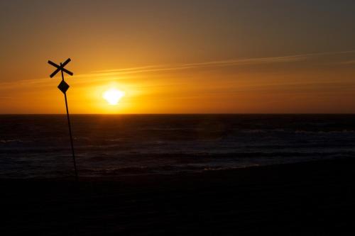 a pole with a cross on the beach at sunset at Jugendherberge Westerland in Westerland (Sylt)