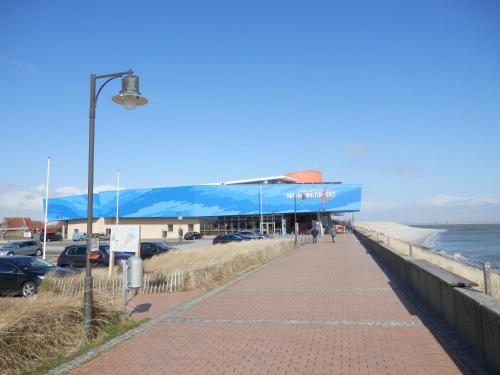 a sidewalk next to the beach with a blue building at Jugendherberge Westerland in Westerland (Sylt)