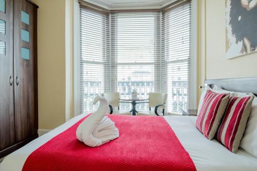 a bedroom with a bed with a towel animal on a red blanket at New Steine Hotel - B&B in Brighton & Hove