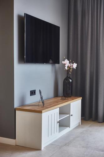 a television on top of a white cabinet with a vase of flowers at Gagarin Plaza Luxury Sea View Apartments in Odesa