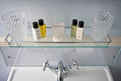 a glass shelf above a sink with bottles and glasses at The Old Vicarage Hotel & Restaurant in Bridgwater