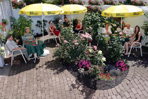 eine Gruppe von Menschen, die in einem Garten mit Sonnenschirmen sitzen in der Unterkunft Astoria Hotel in Trier