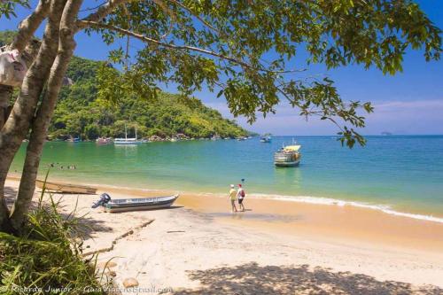 duas pessoas numa praia com um barco em Hospedagem Lagoinha em Ubatuba