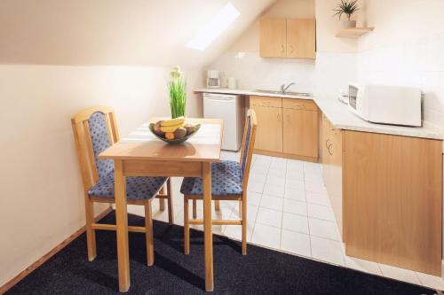 a small kitchen with a wooden table and chairs at Apartman Szanyi in Bük